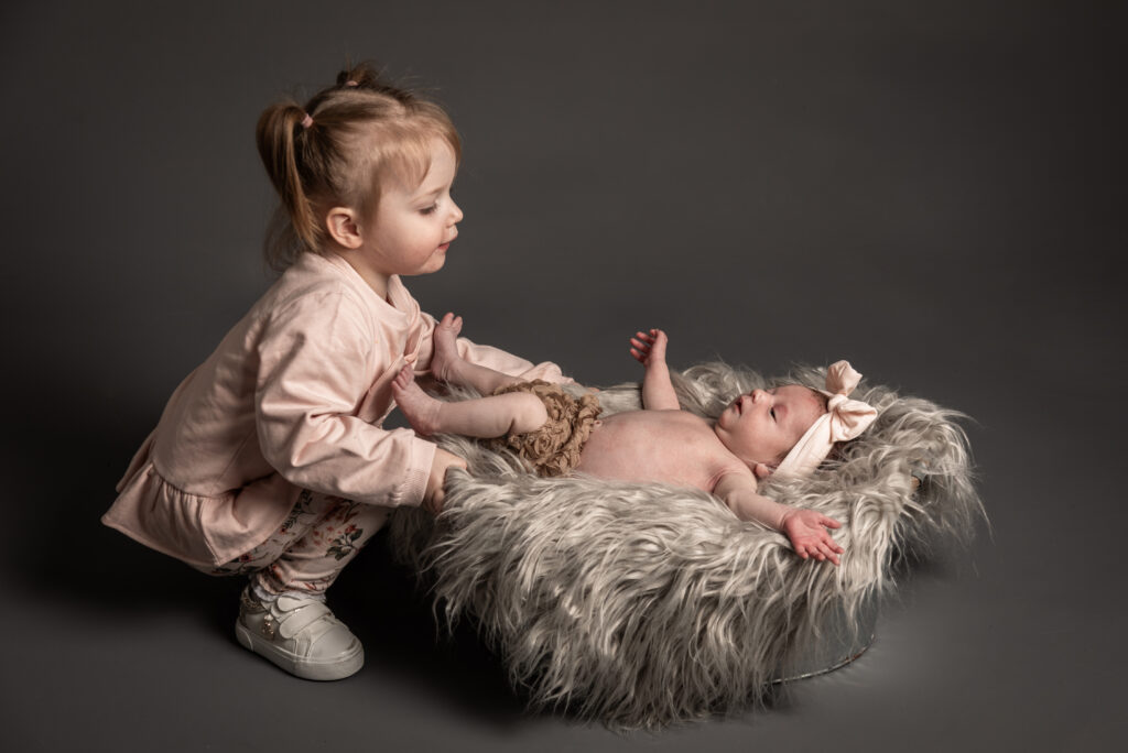 newborn baby with sister looking on